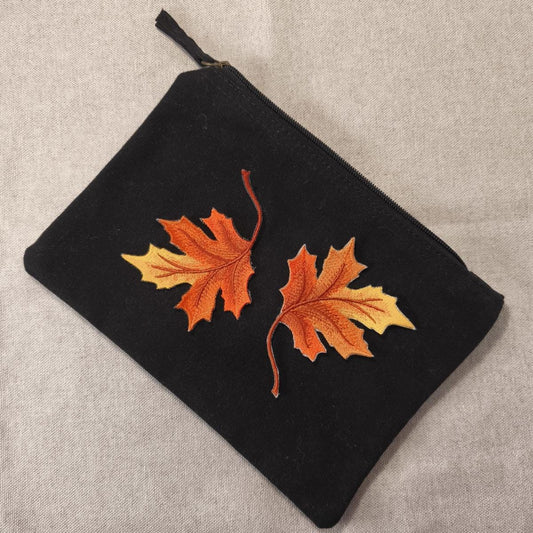 Zwei Ahornblätter Aufnäher zum aufbügeln in Herbstfarben auf einem schwarzen Etui als Beispiel auf einem neutralen Hintergrund