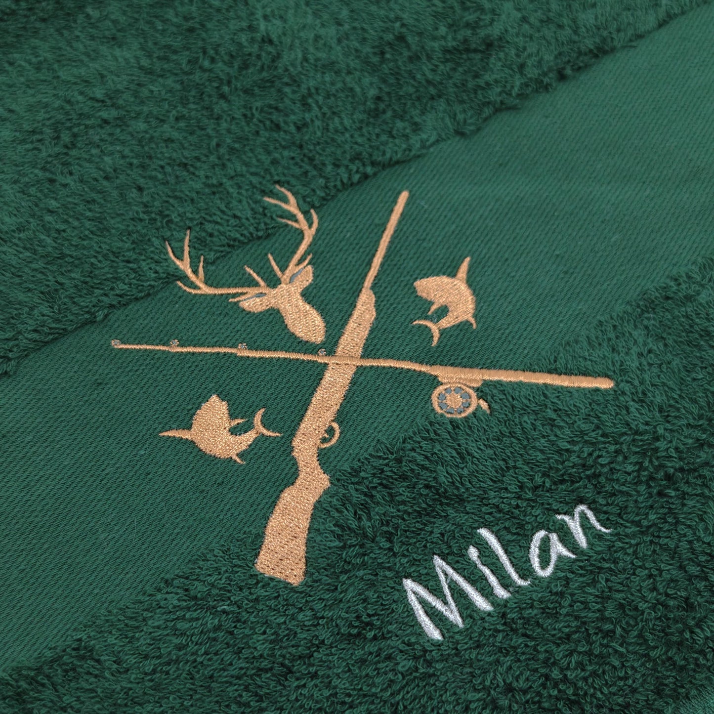 Nahaufnahme der Jagd und Angeln Motiv mit Namen Stickerei um die Qualität zu zeigen. Die Stickerei ist auf einem dunkelgrünen Handtuch angefertigt.