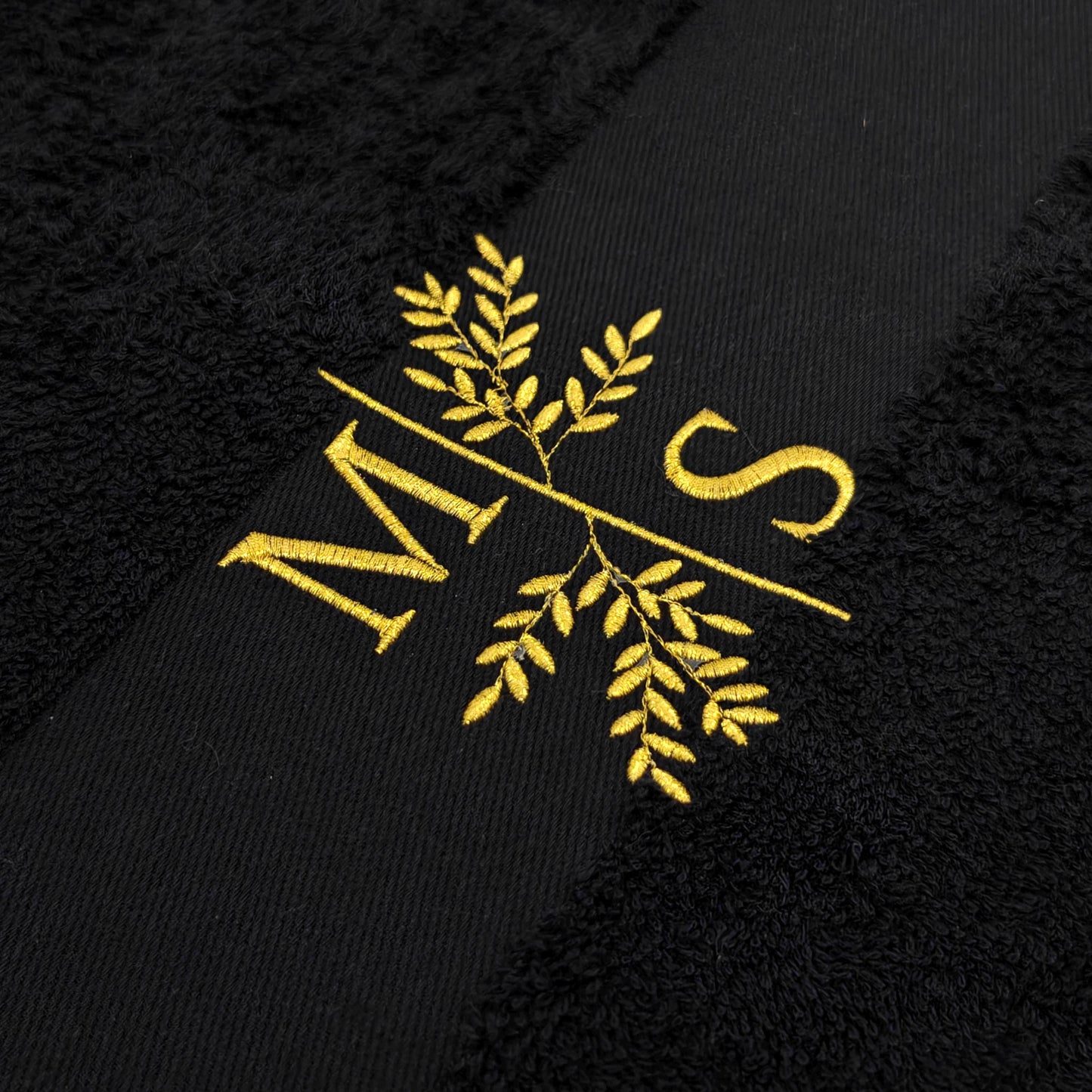 Detail Stickerei Initialen mit Blumenmotiv auf personalisiertem schwarzem Handtuch